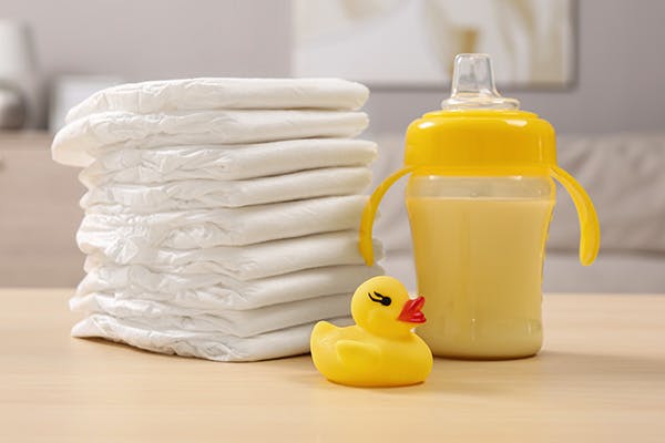 Table with a pile of towels, a rubber duck and a trainer cup