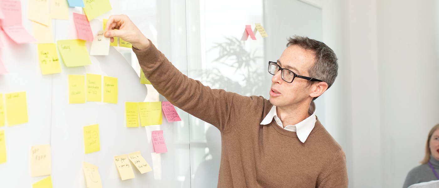 Person puts sticky note on Kanban board