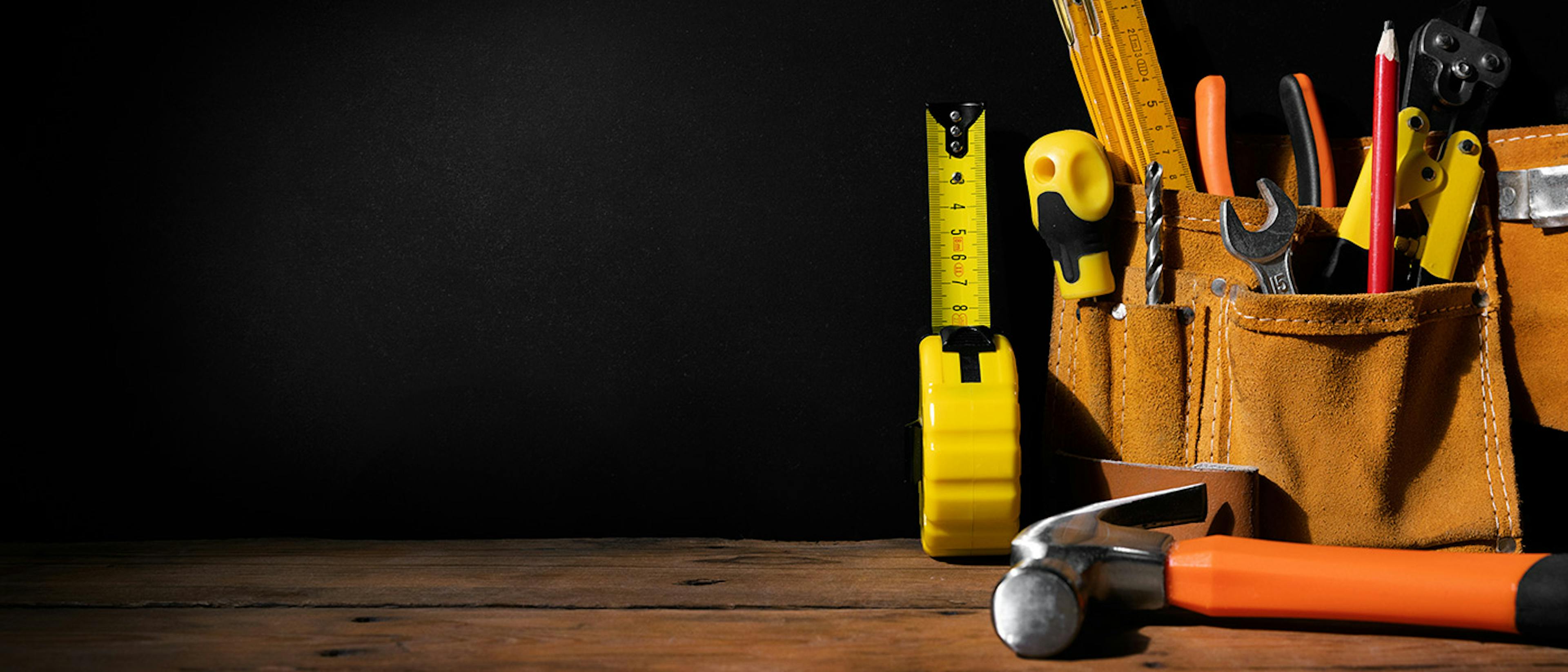 A workbench with a set of tools on it, some of them in a tool belt.