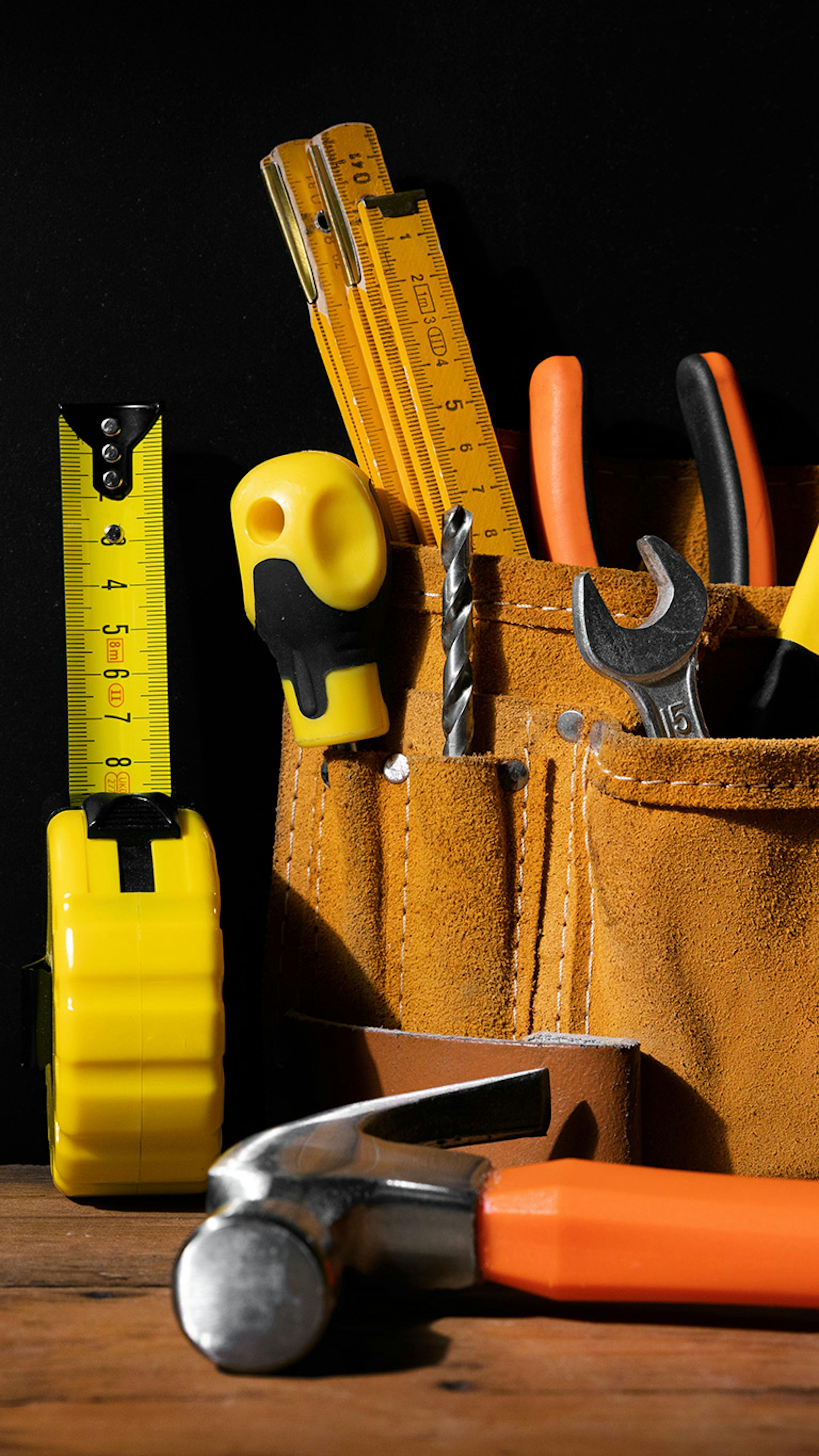 A workbench with a set of tools on it, some of them in a tool belt.