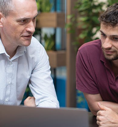 Two people in discussion behind a laptop