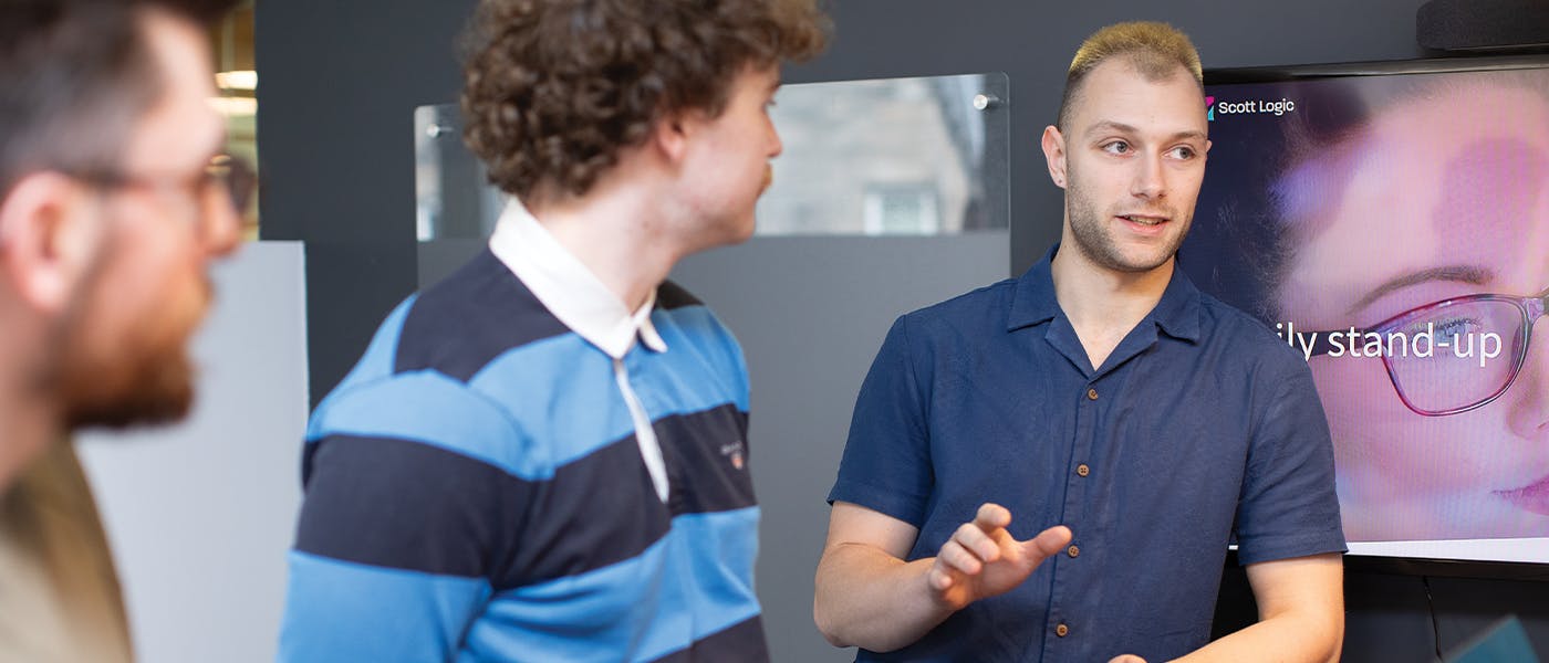 Three people in discussion in front of a TV screen