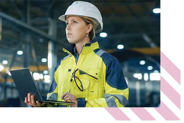 Woman wearing a hardhat and hi-vis, holding a laptop