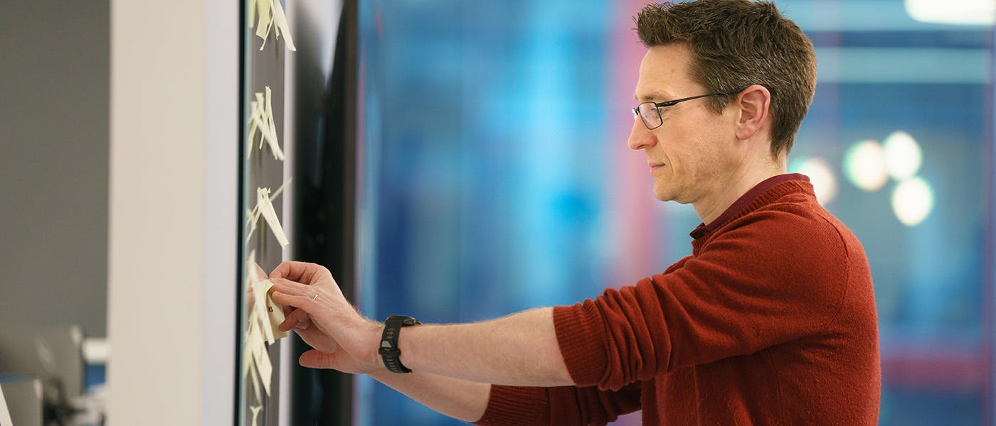 Man adding sticky notes to whiteboard