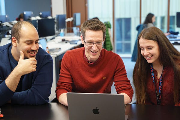Two people in a stand-up meeting looking at a laptop screen