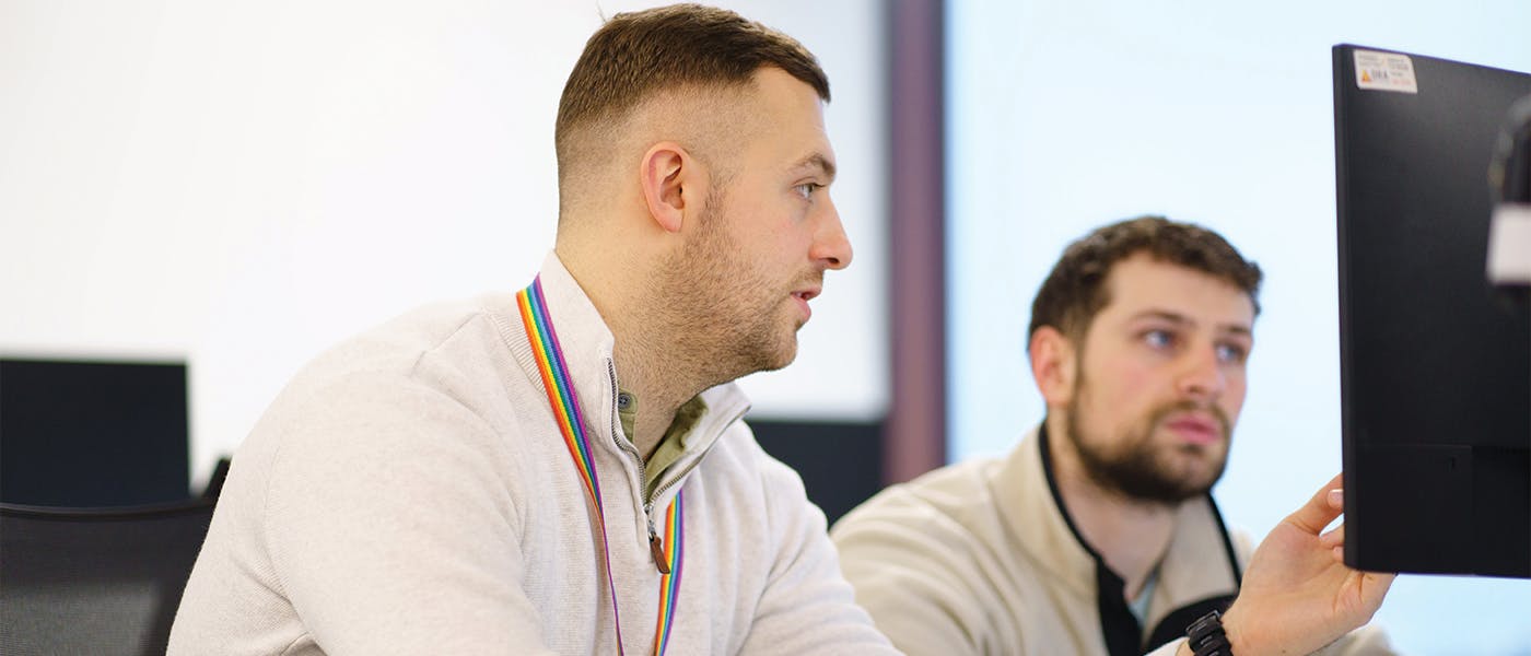 Two people in discussion at a computer monitor