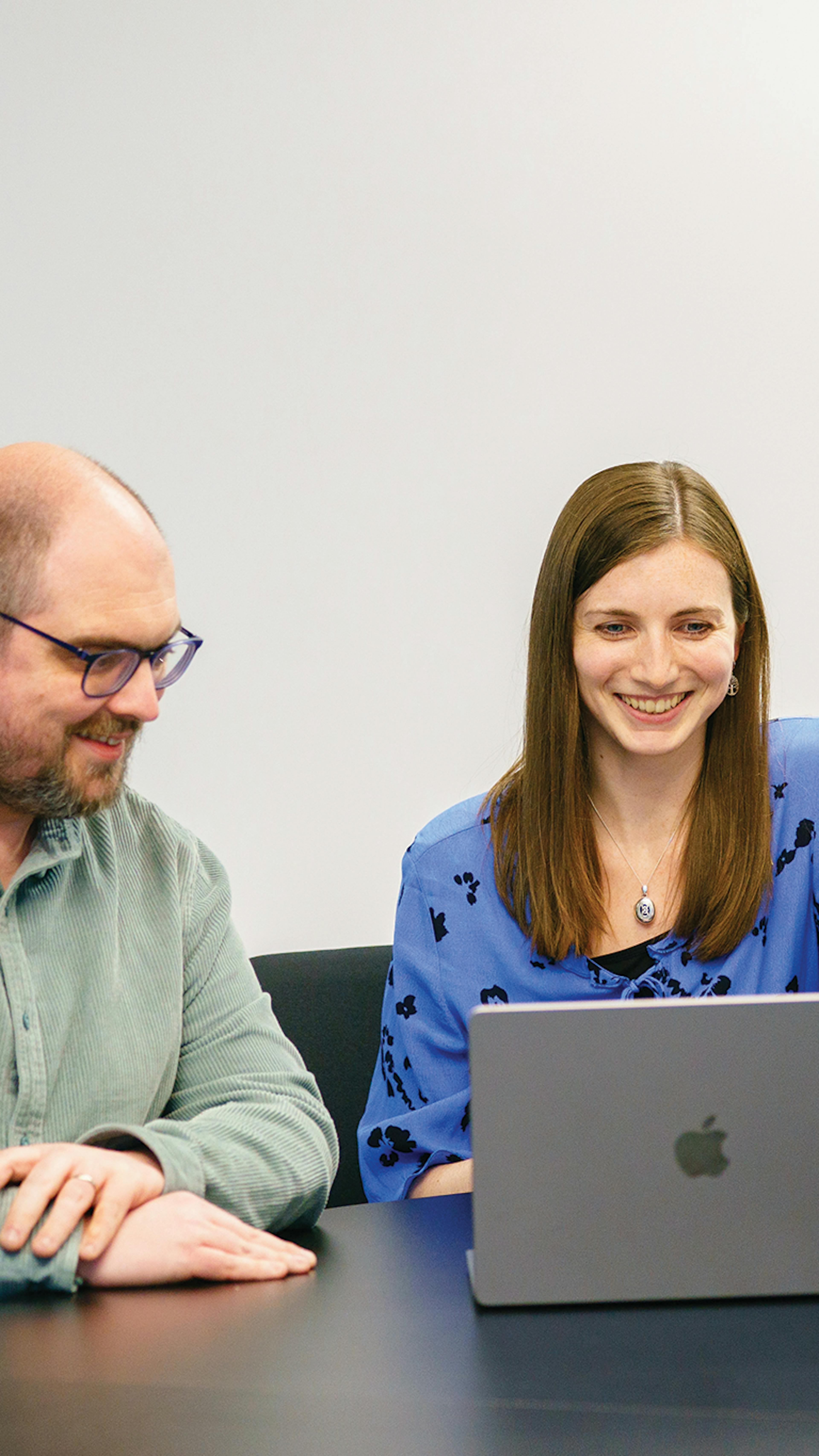 Two people sat at a desk behind a laptop