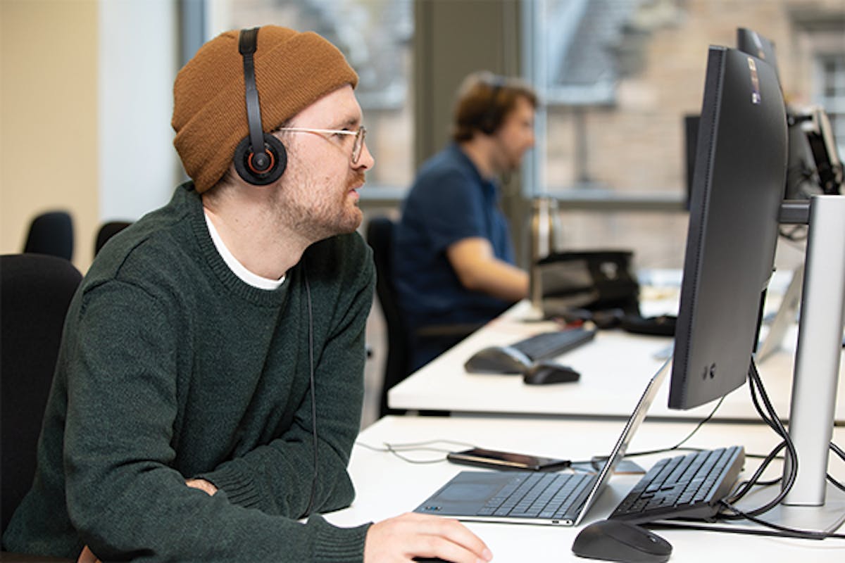 Person wearing headphones working on a laptop