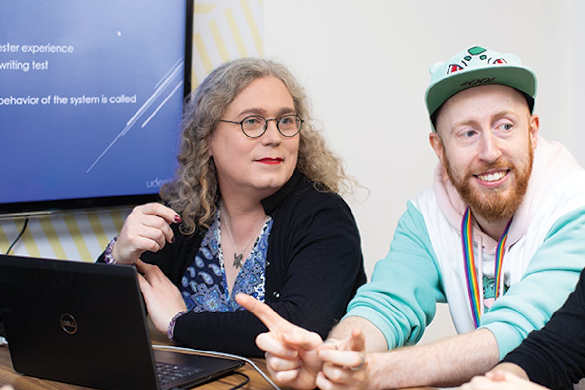 Two people in discussion around a laptop
