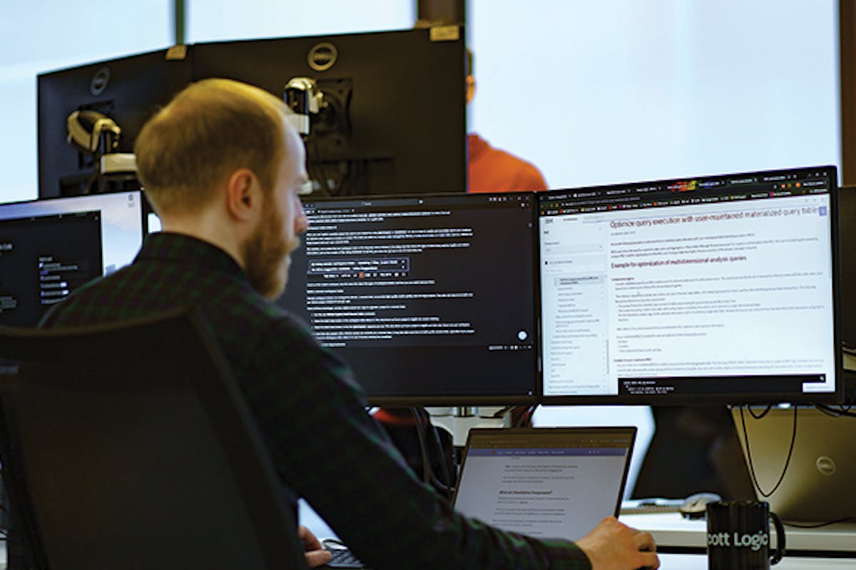 Person sat at desk with code on computer screen