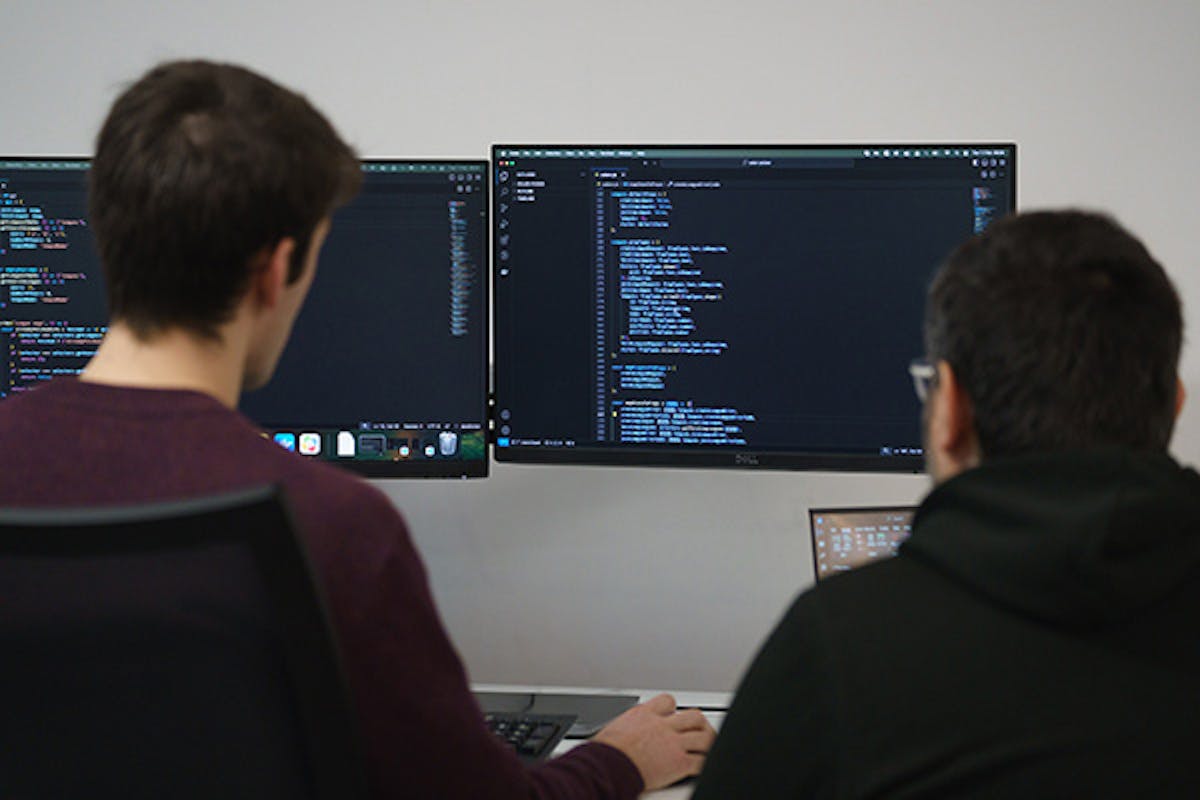 Two people examining some code on a computer screen
