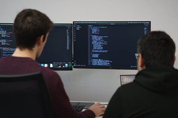 Two people examining some code on a computer screen