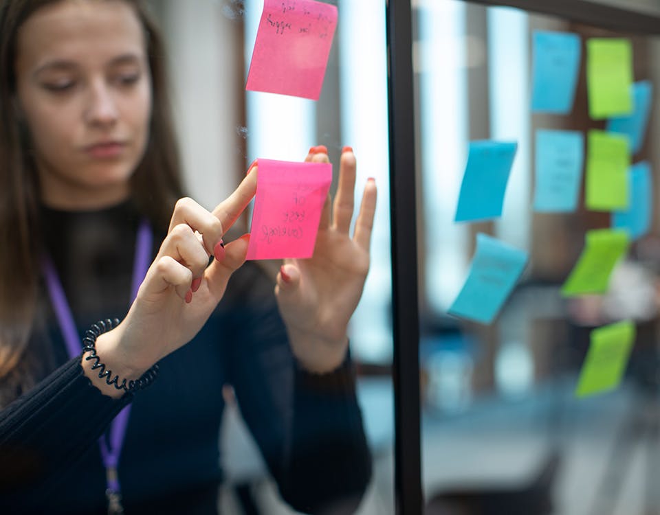 Woman placing sticky notes on a window in a meeting