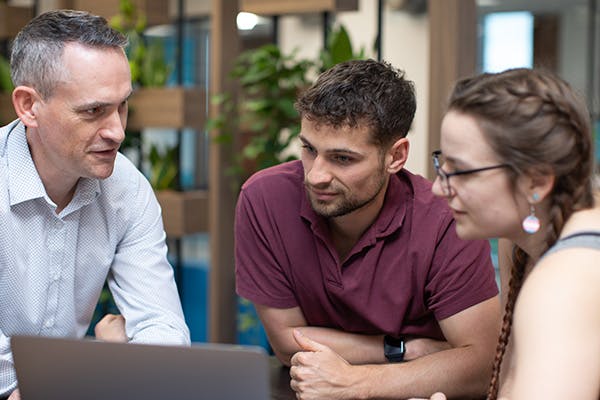 Three people in a meeting looking at a laptop