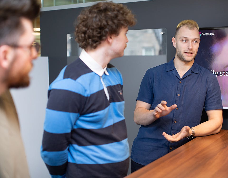 Three people in discussion in front of a TV screen