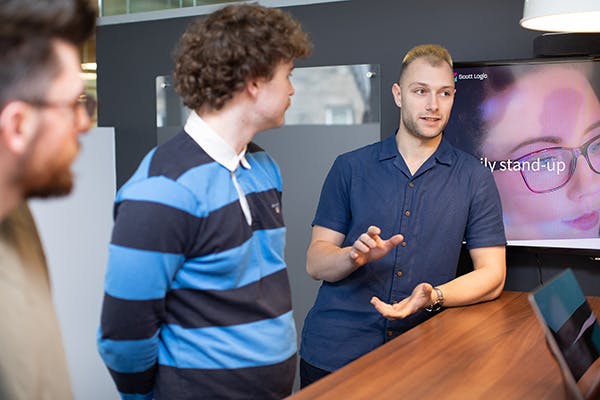Three people in discussion in front of a TV screen