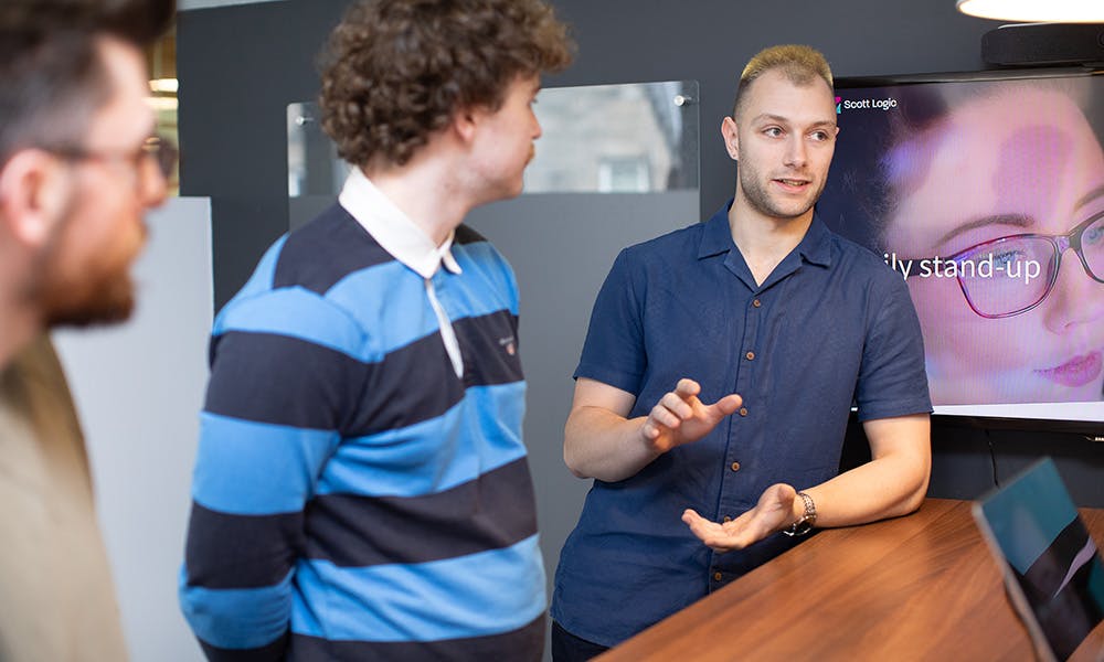 Three people in discussion in front of a TV screen