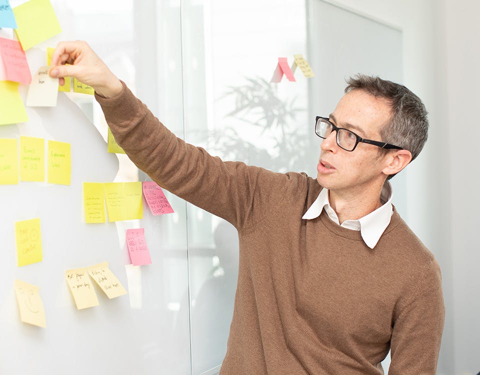 Man placing sticky note on a whiteboard