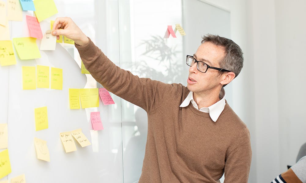 Man placing sticky note on a whiteboard