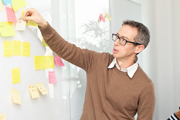 Man placing sticky note on a whiteboard