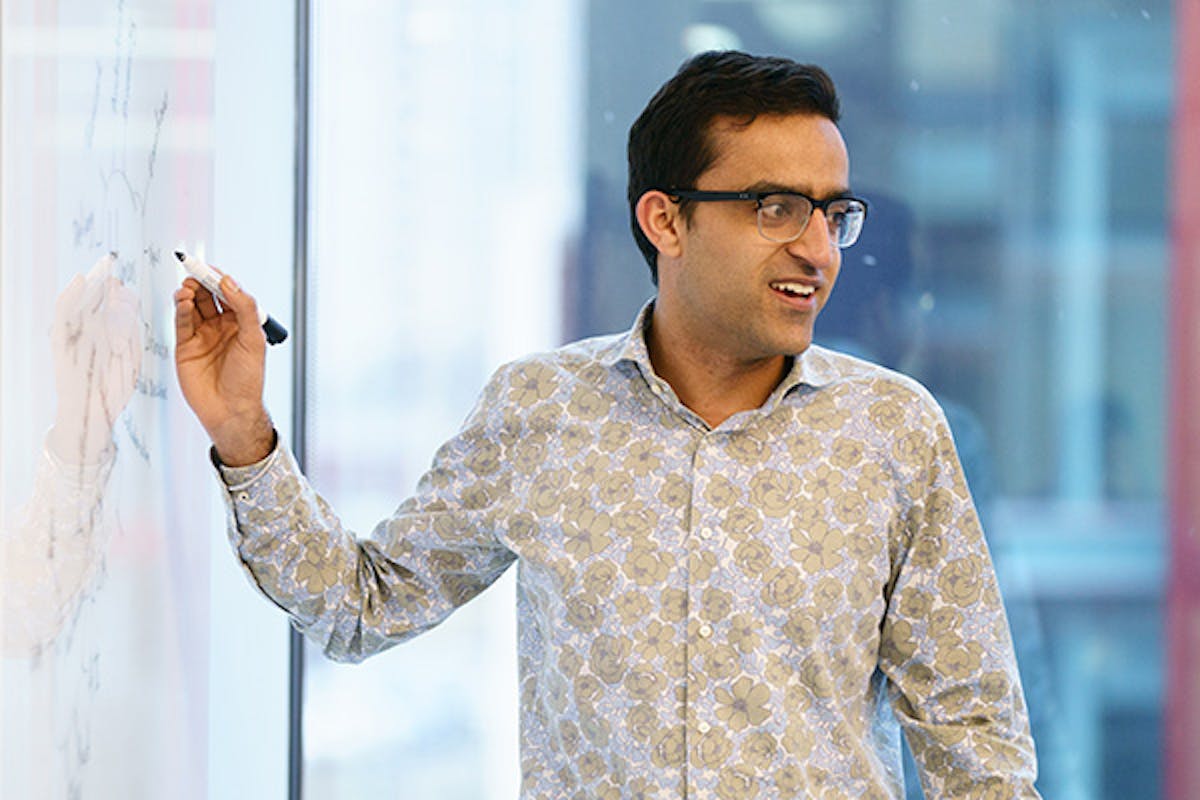 Man presenting in a meeting and writing on a whiteboard