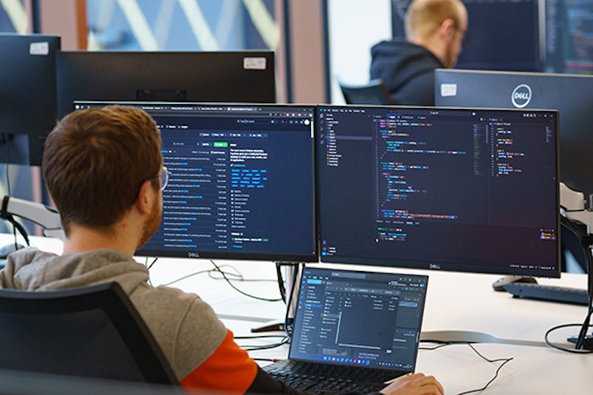 Software developer using three screens in an office setting