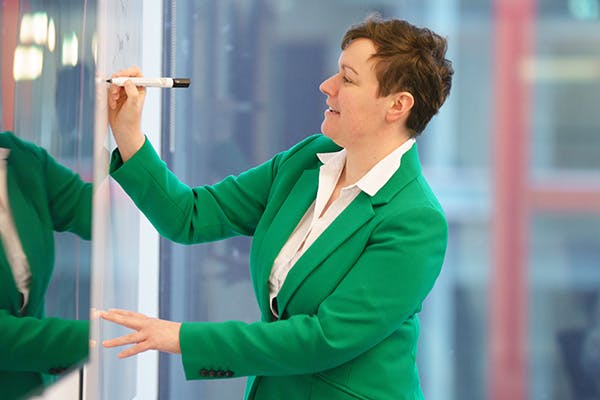 Woman in a meeting writing on a whiteboard