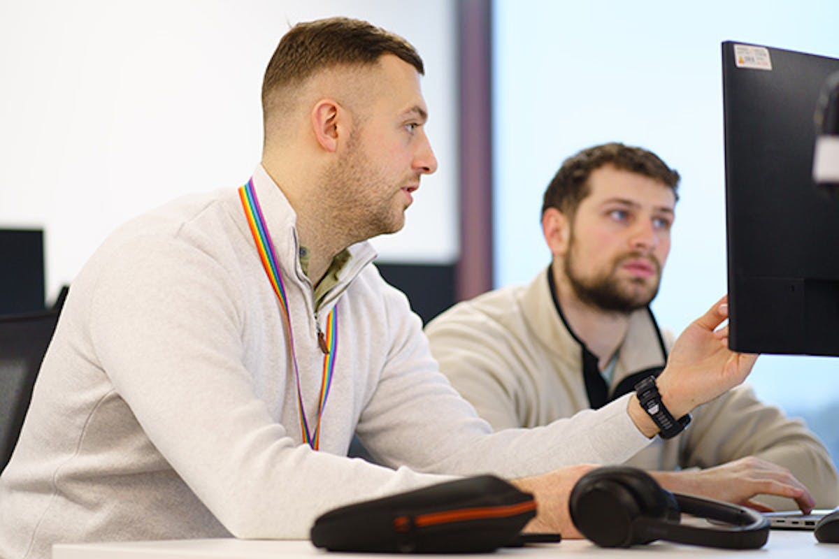 Two developers discussing some code on a computer screen