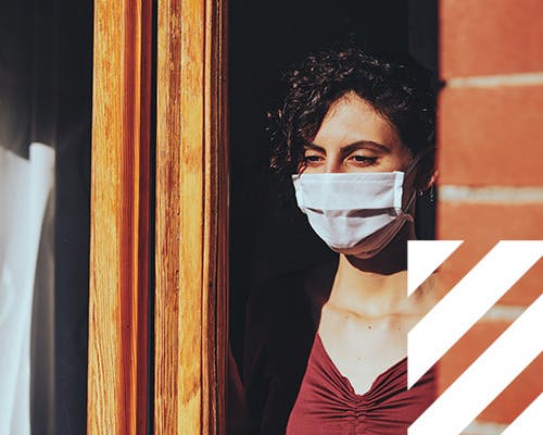 Woman wearing a face mask looking out of a window
