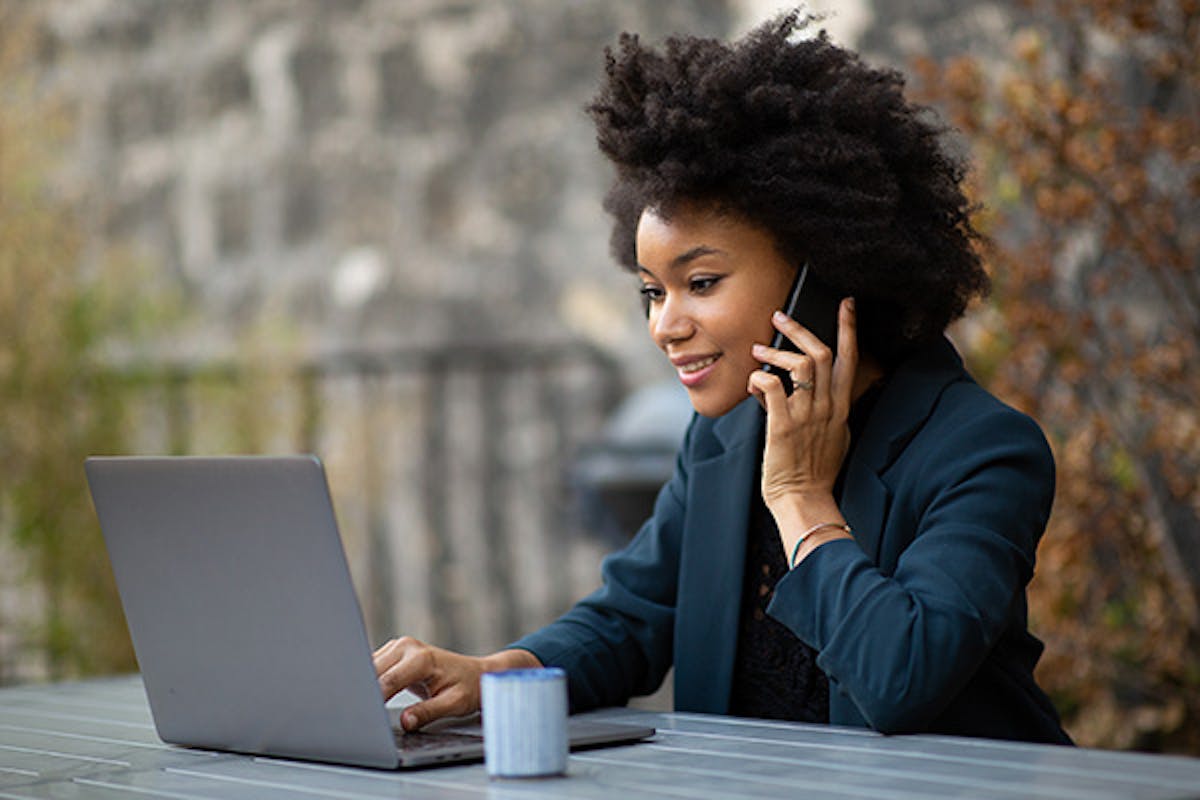 Woman working with laptop while taking a phone call