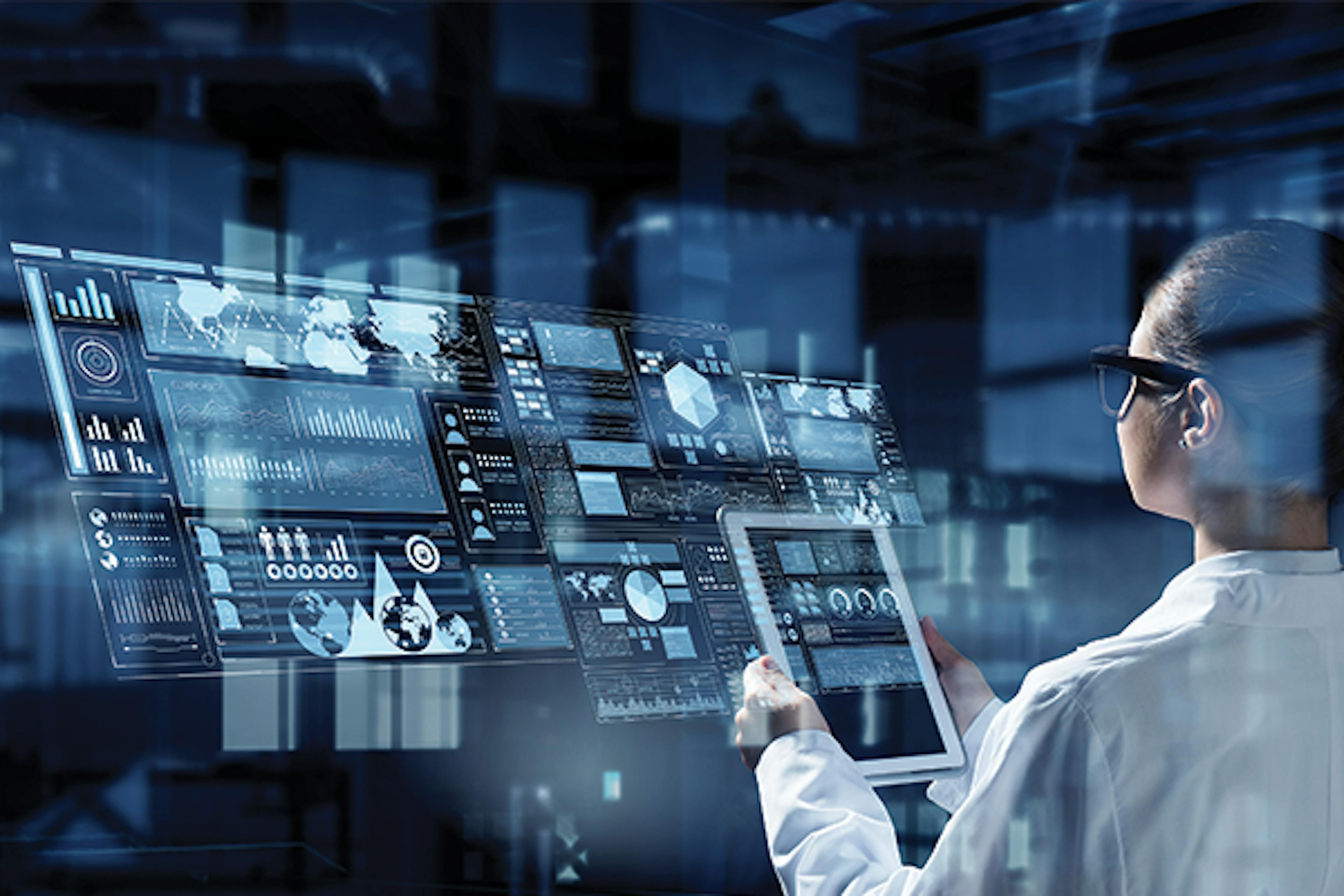 Person in white lab coat looks at tablet with visualisation of data