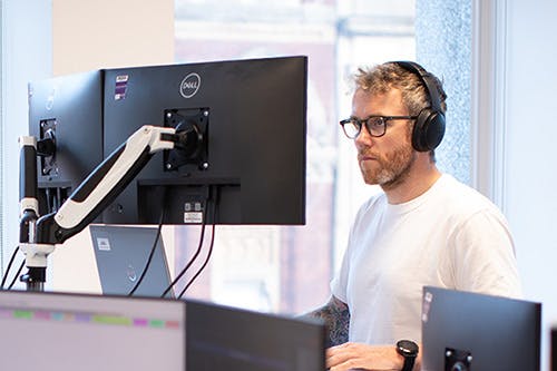Man working at a computer, wearing headphones