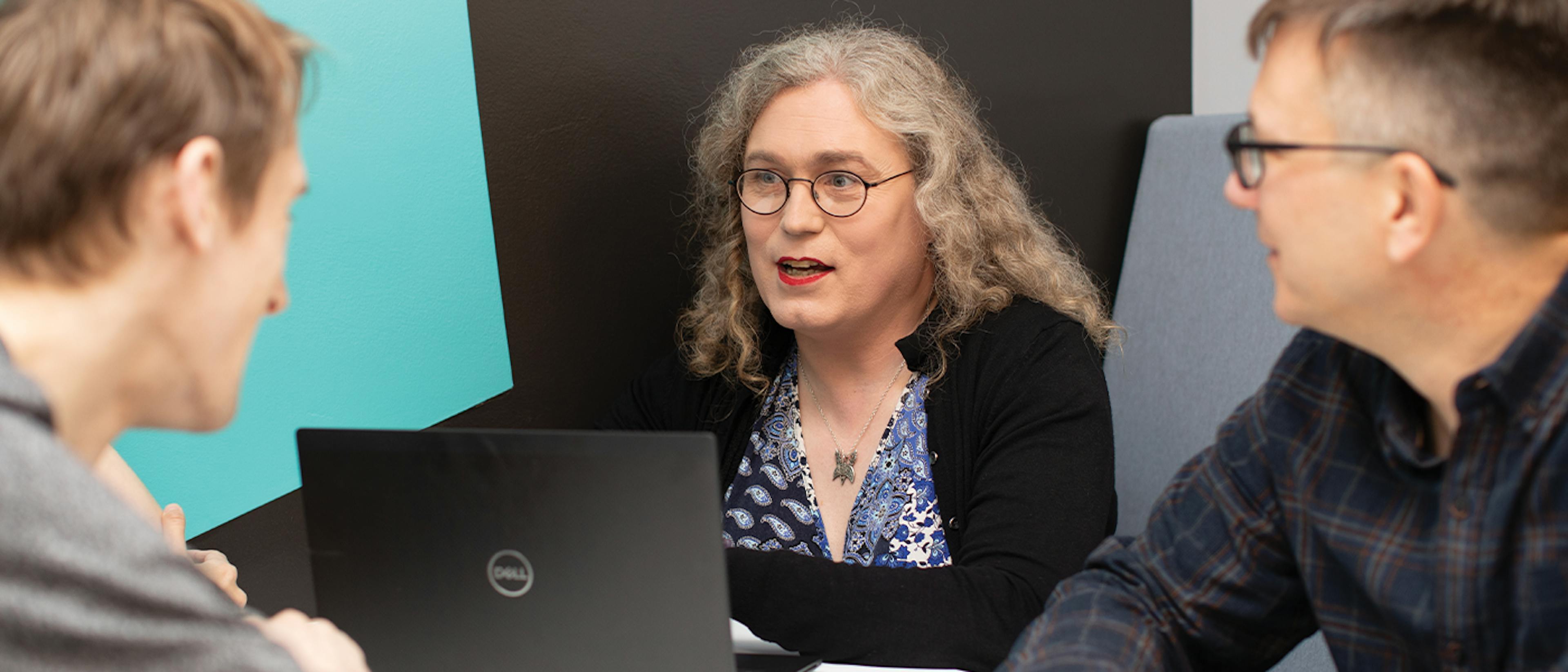 Three individuals around a laptop