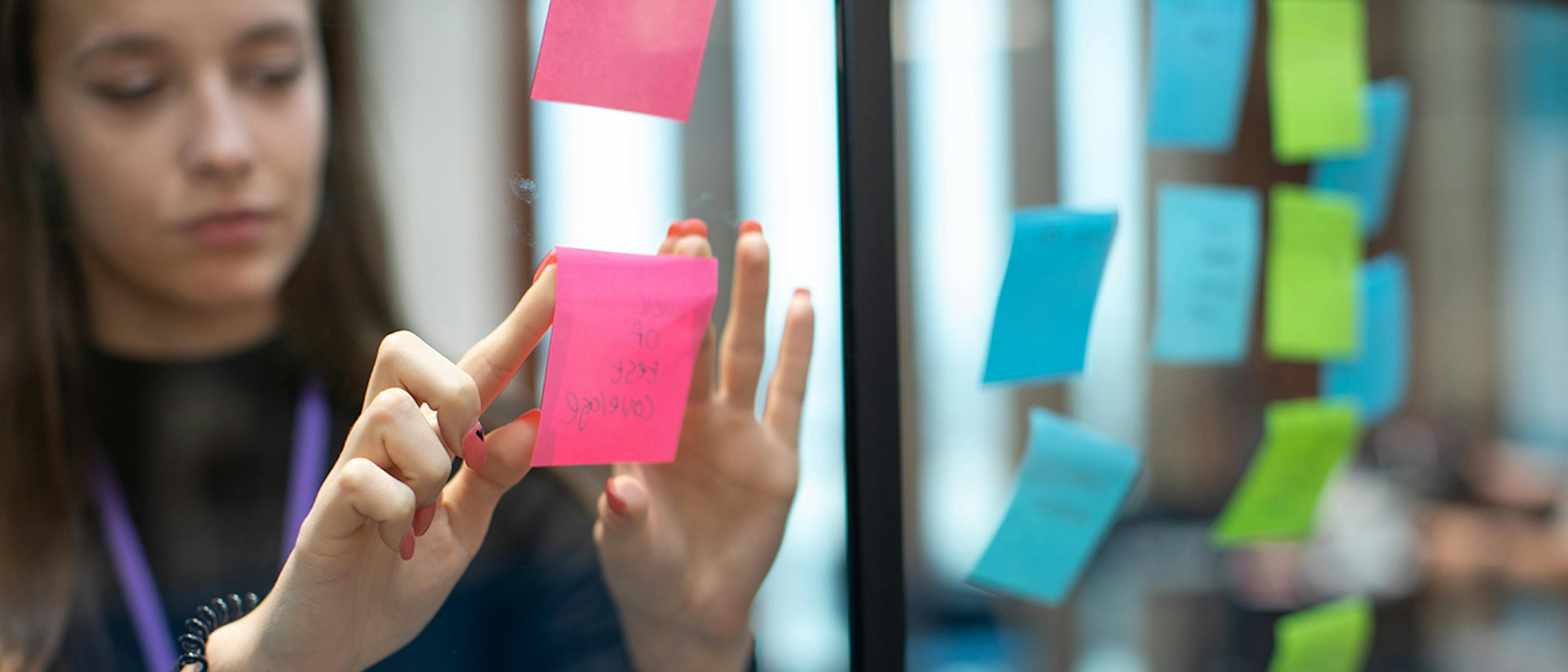 Woman adding sticky notes to a glass wall