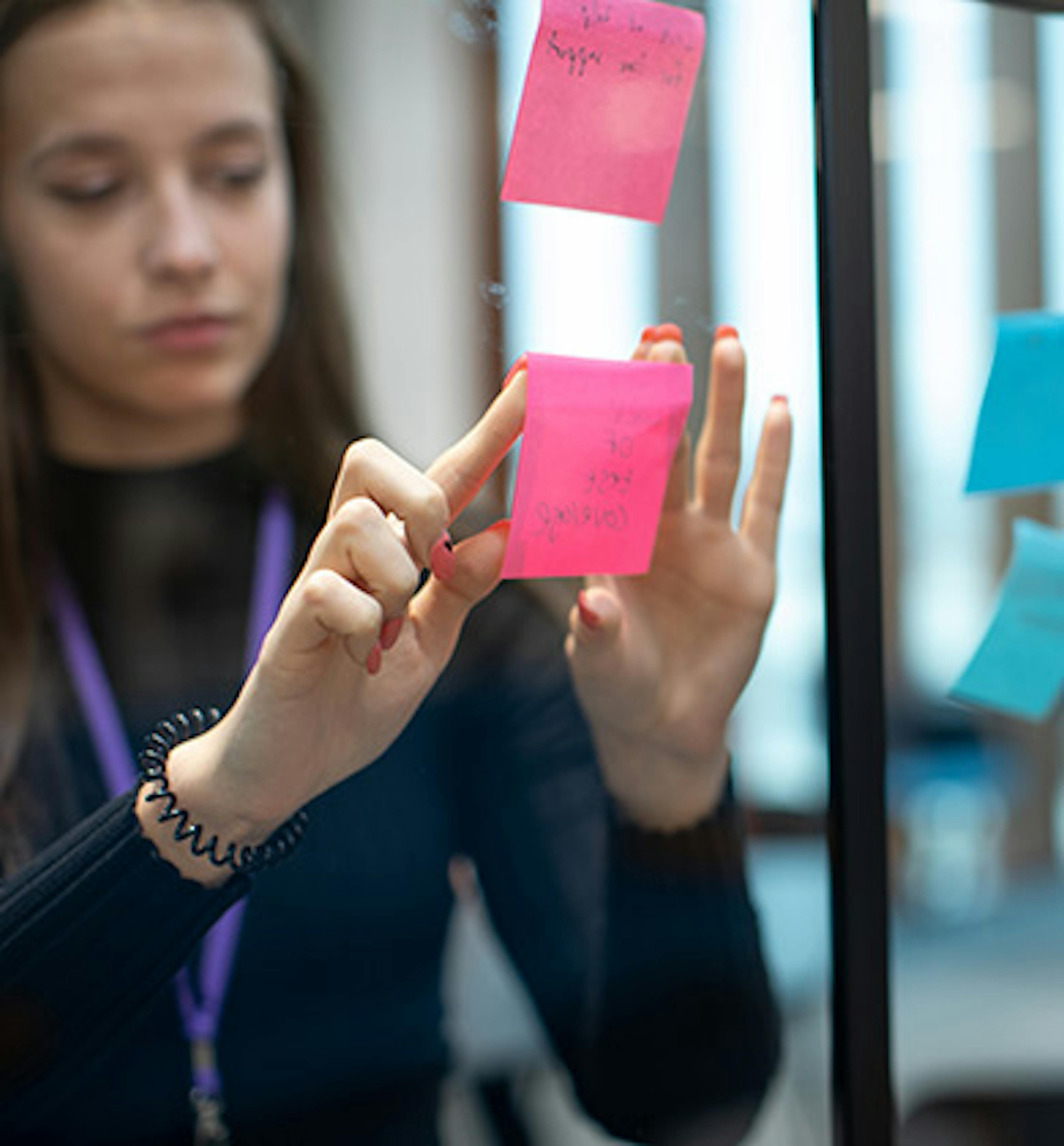 Woman adding sticky notes to a glass wall