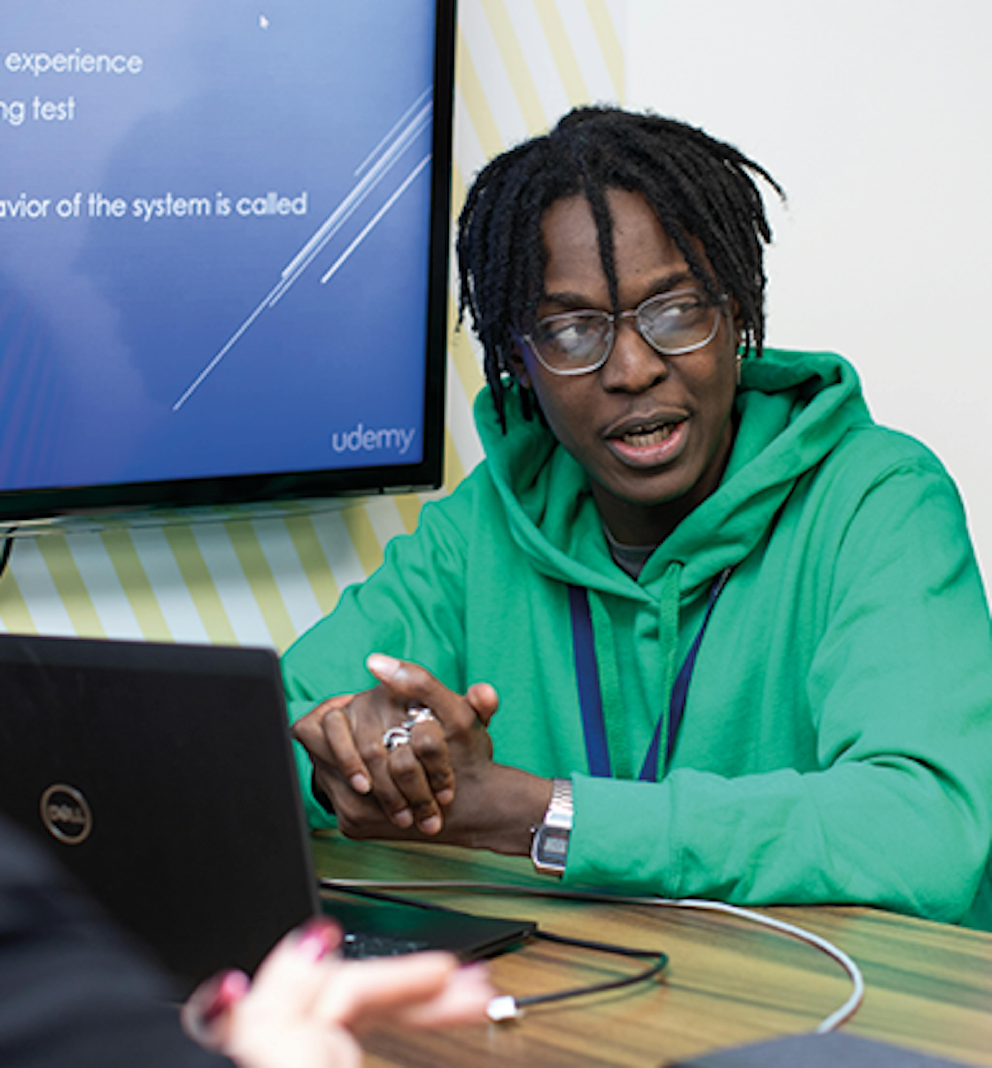 Employee with laptop and big screen behind