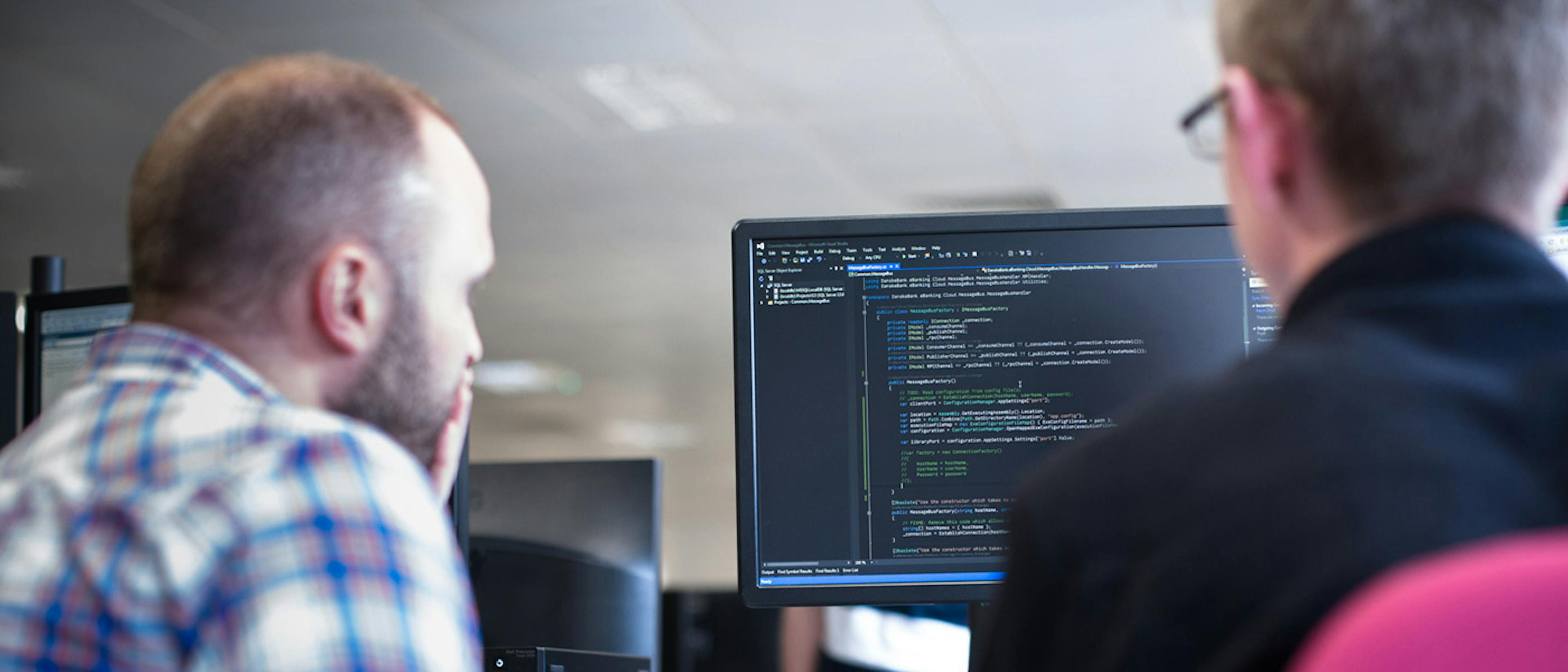 Two people looking at some code on a computer screen