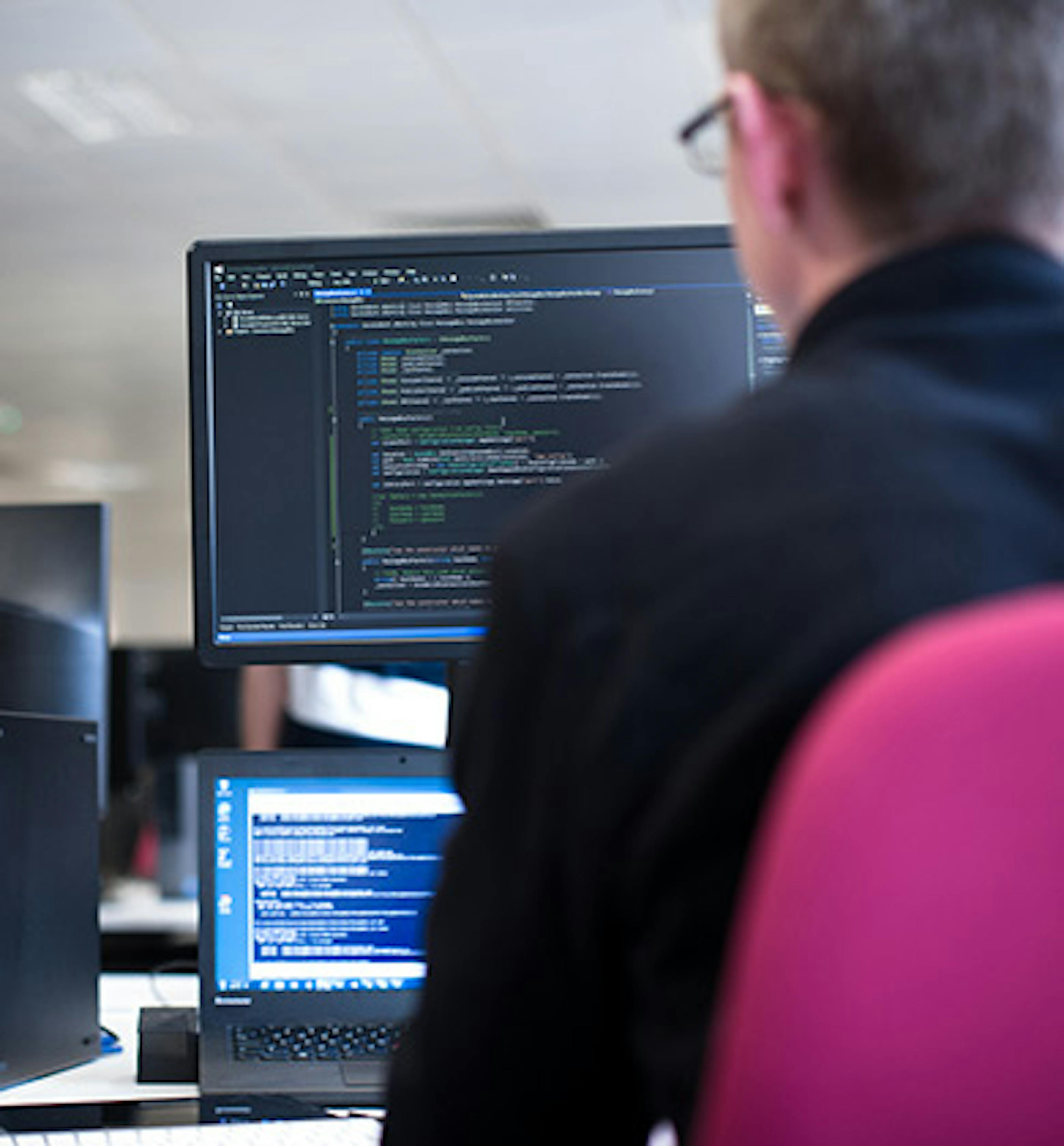 Two people looking at some code on a computer screen