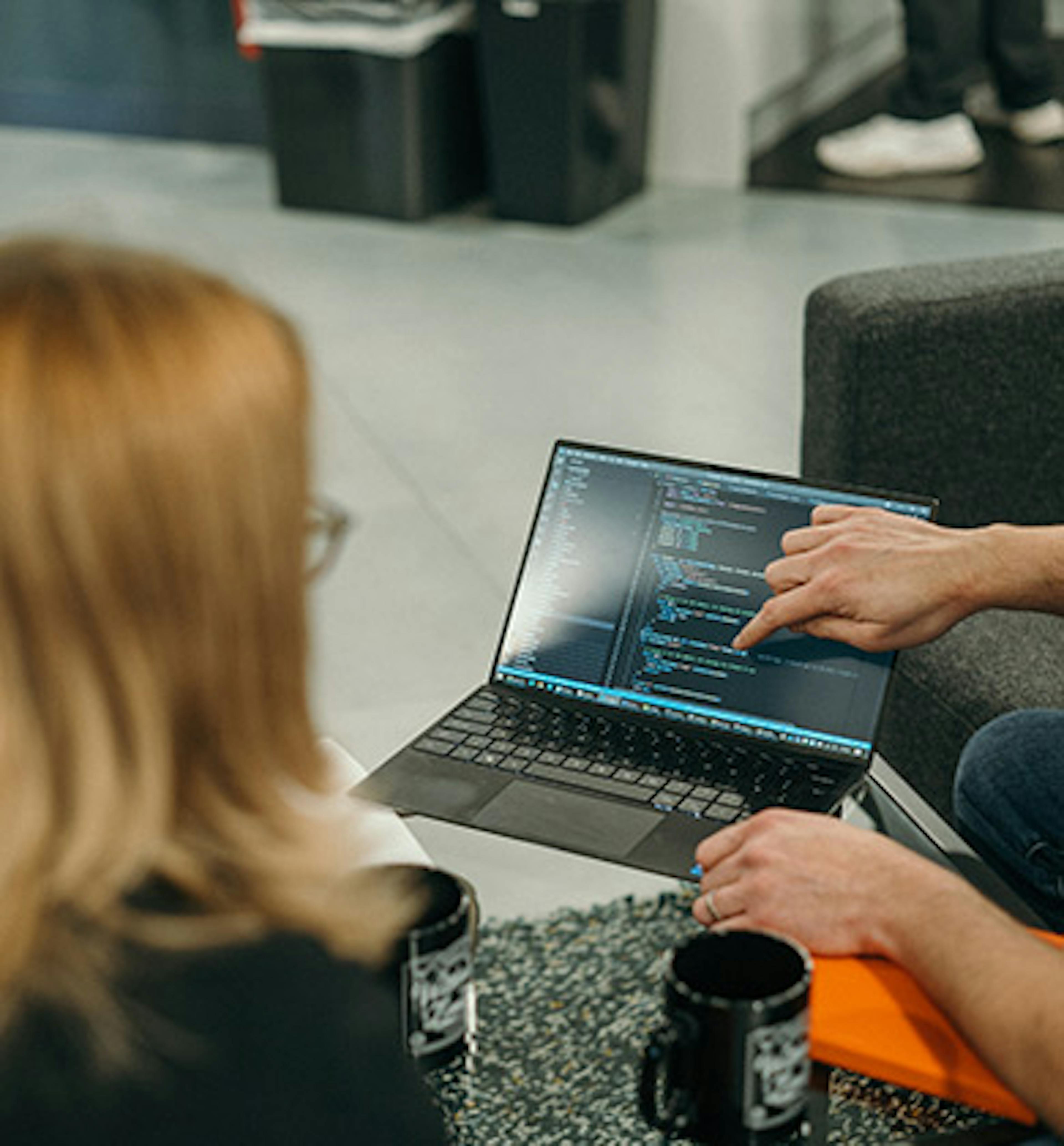 Three people looking at some code on a laptop