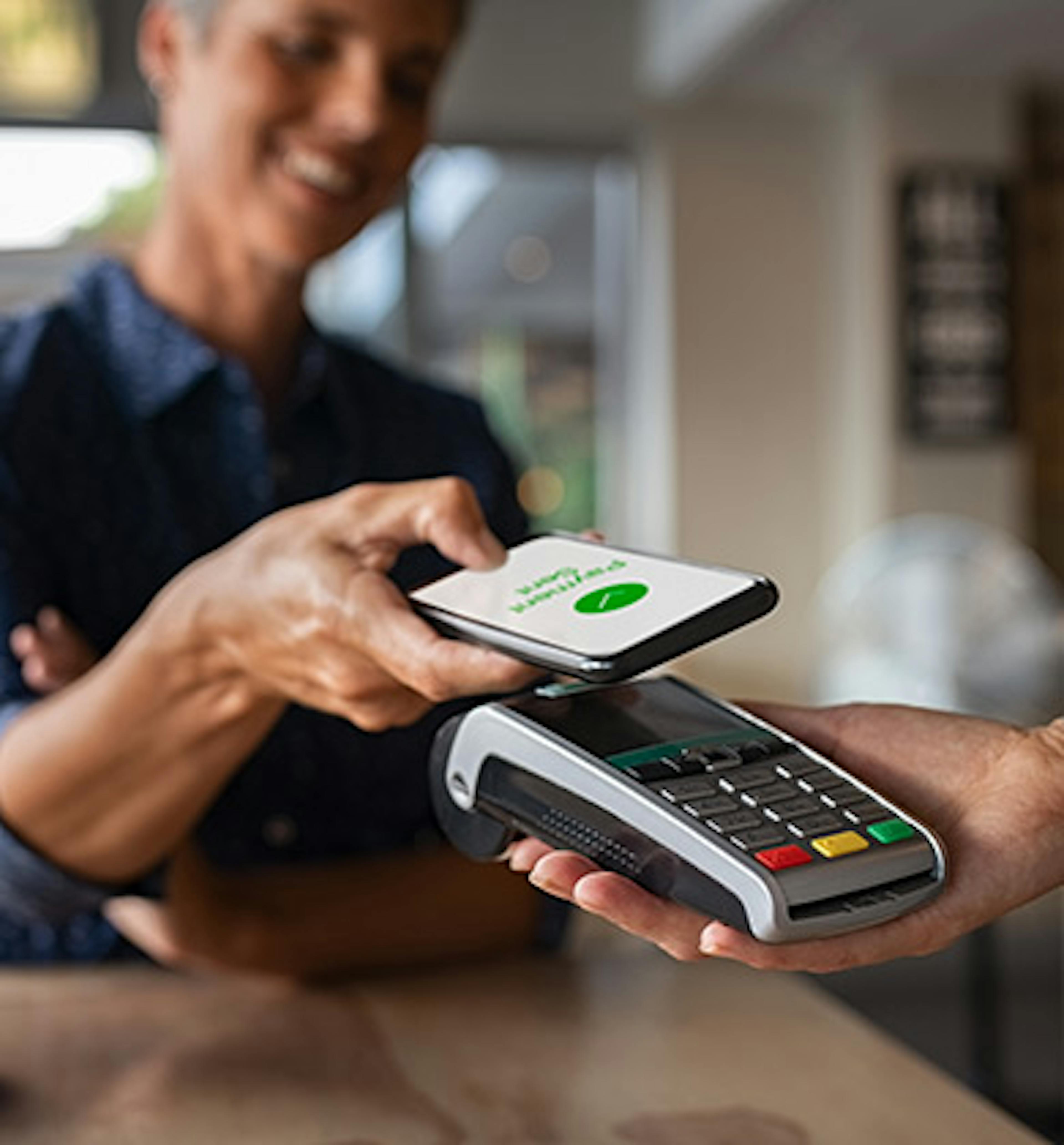 Woman making a mobile payment in a café