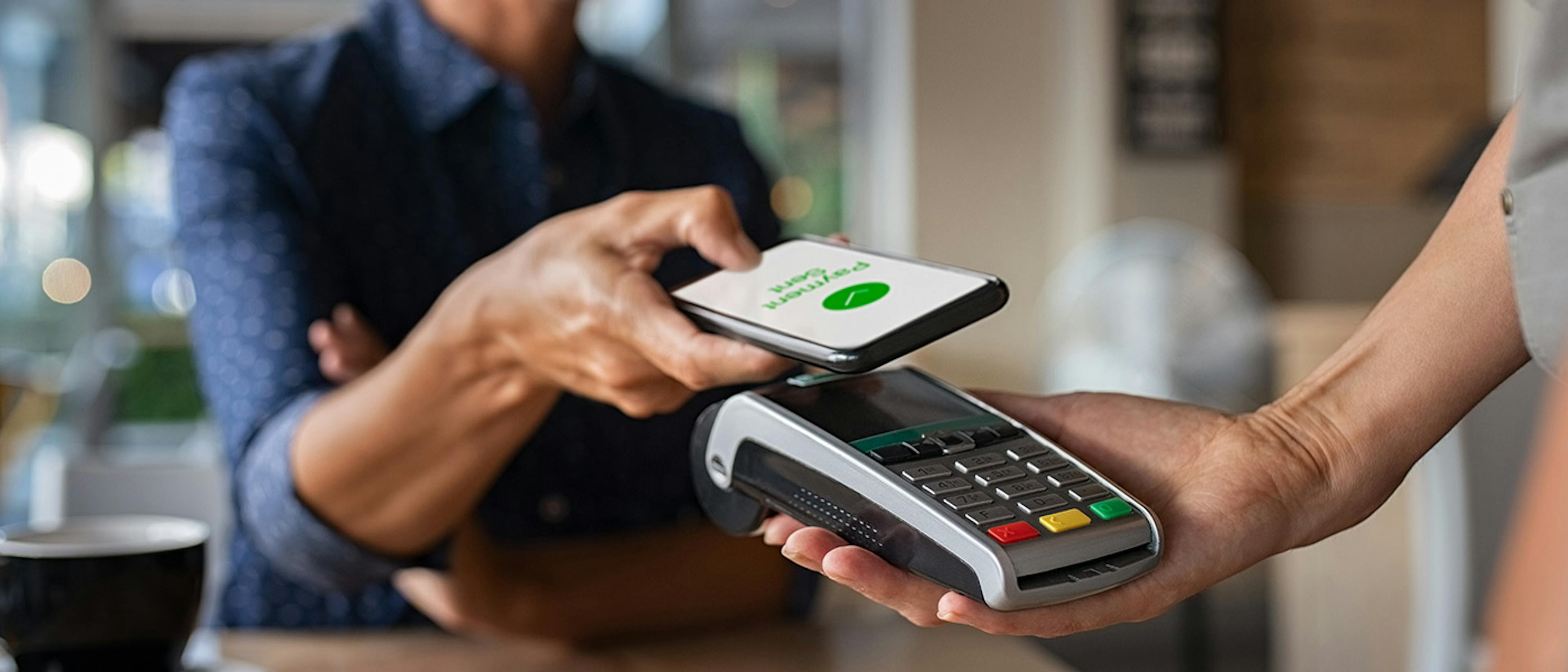 Woman making a mobile payment in a café