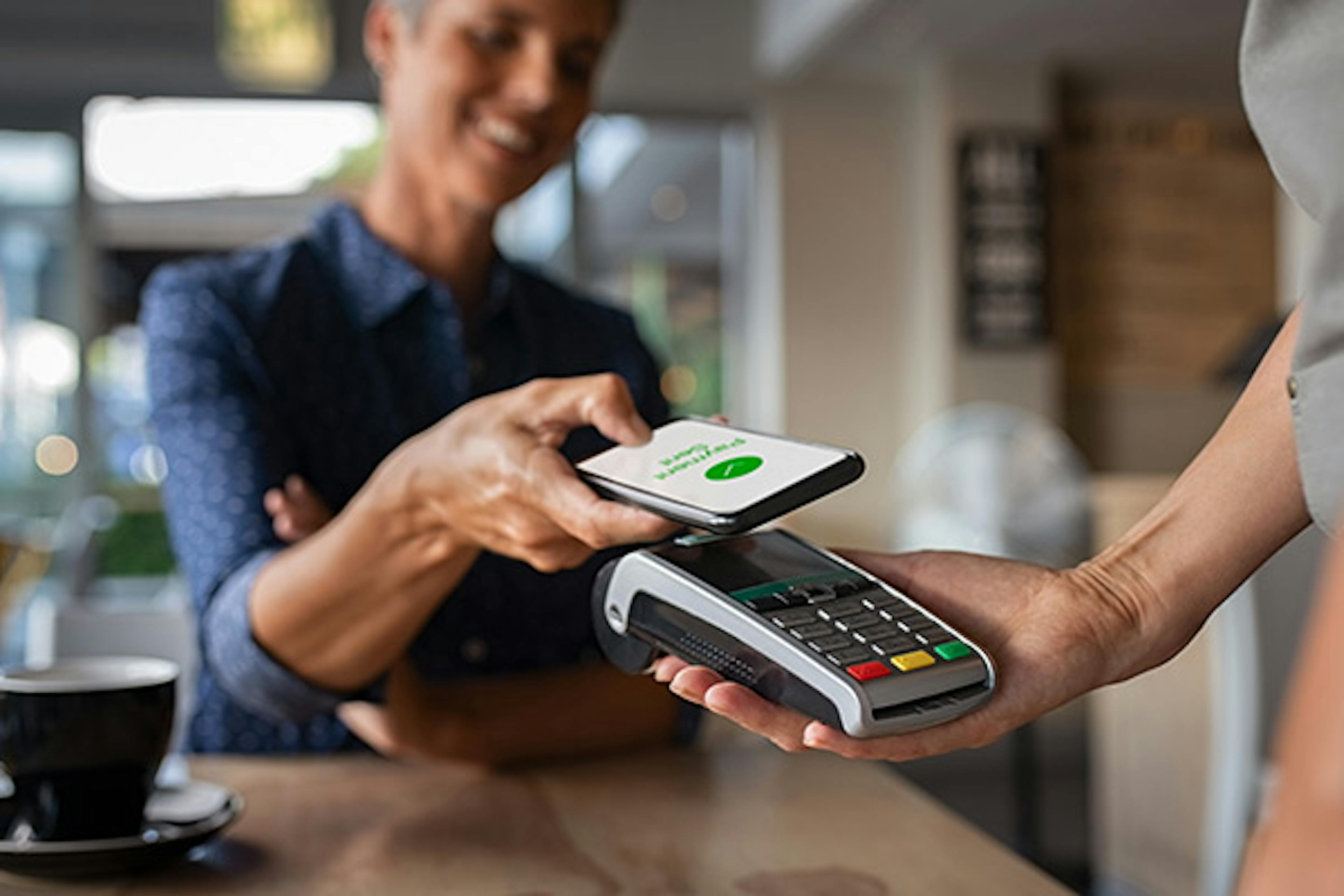 Woman making a mobile payment in a café