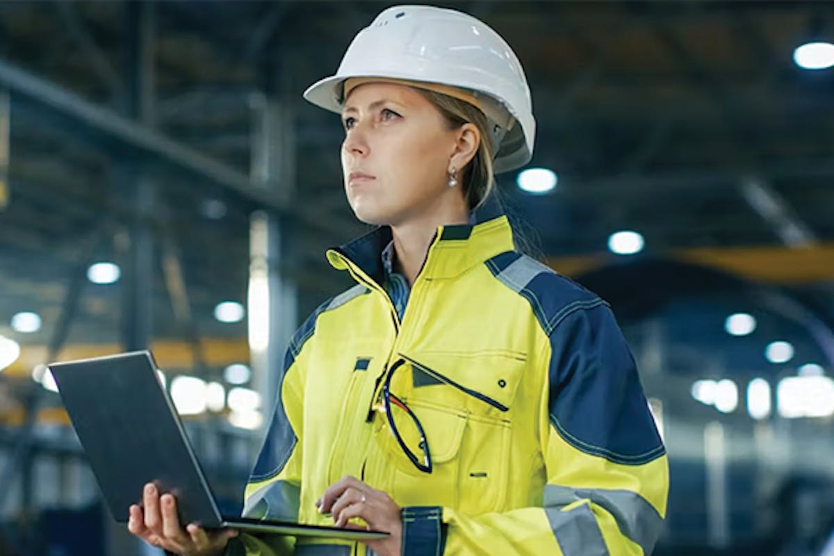 Worker wearing hardhat holding a laptop