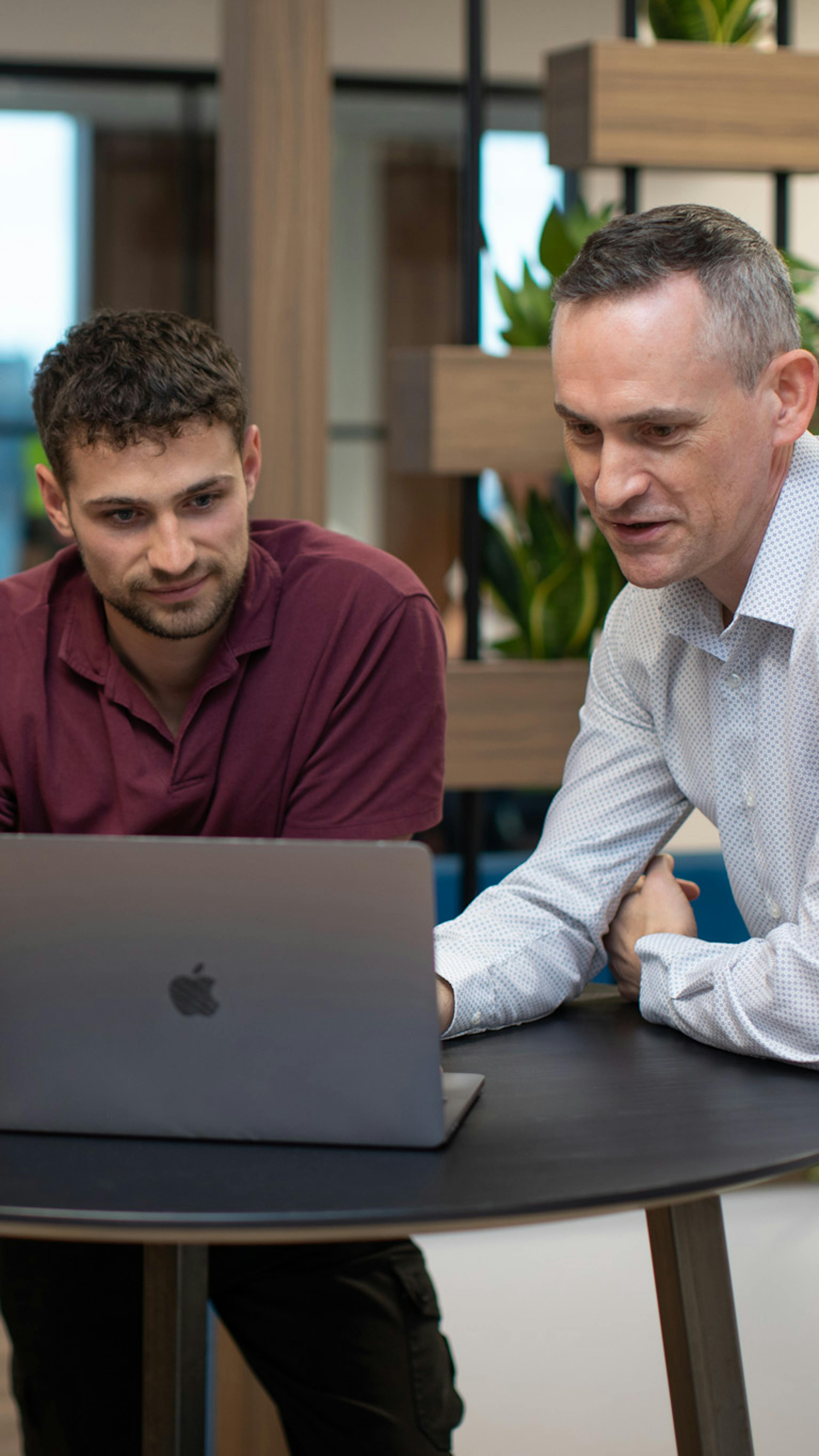 Two people in a stand-up meeting looking at a laptop screen