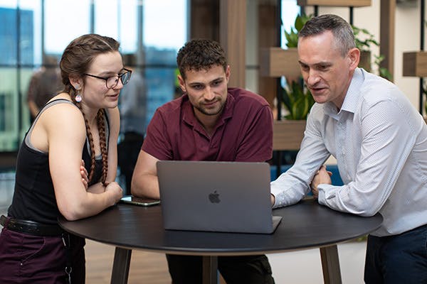 Two people in a stand-up meeting looking at a laptop screen