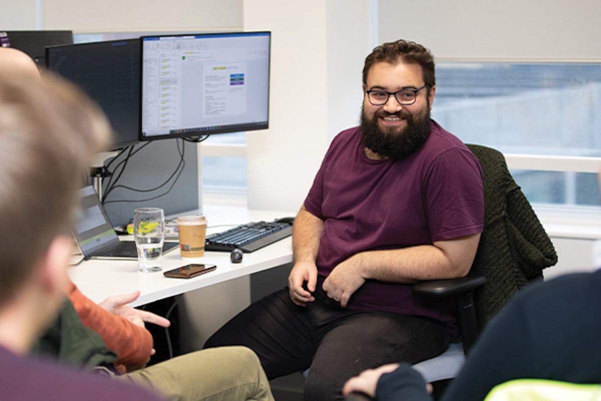 Employee laughing whilst chatting to others around desk