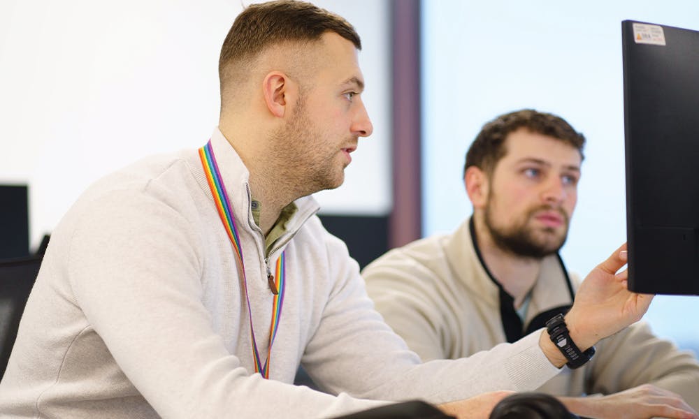 Two people in discussion at a computer monitor