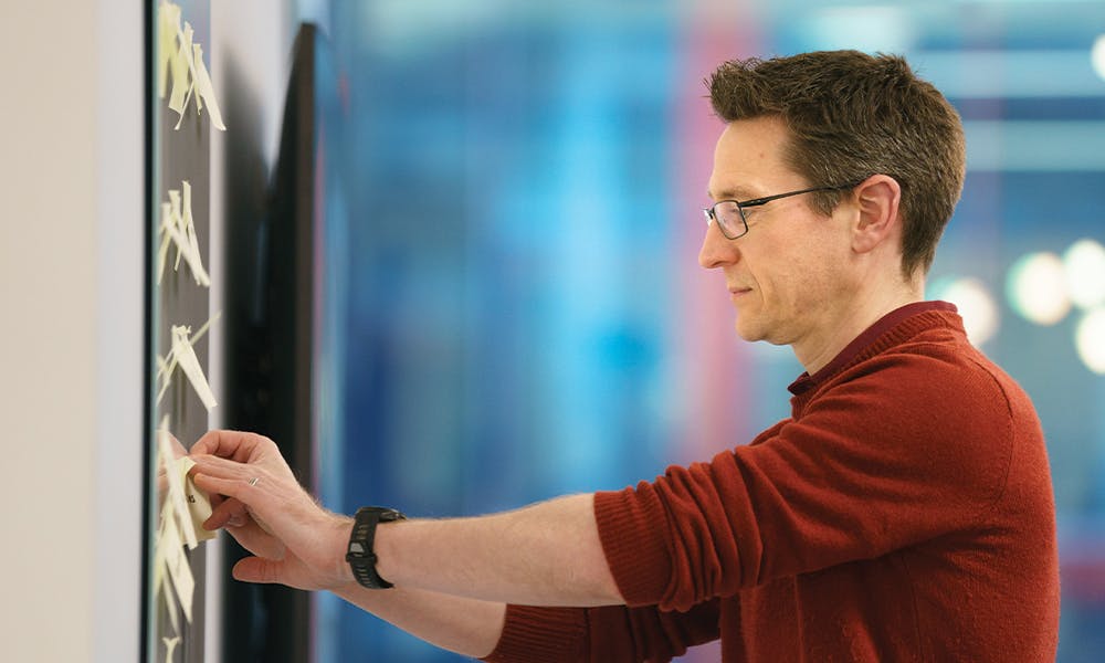 Man adding sticky notes to whiteboard