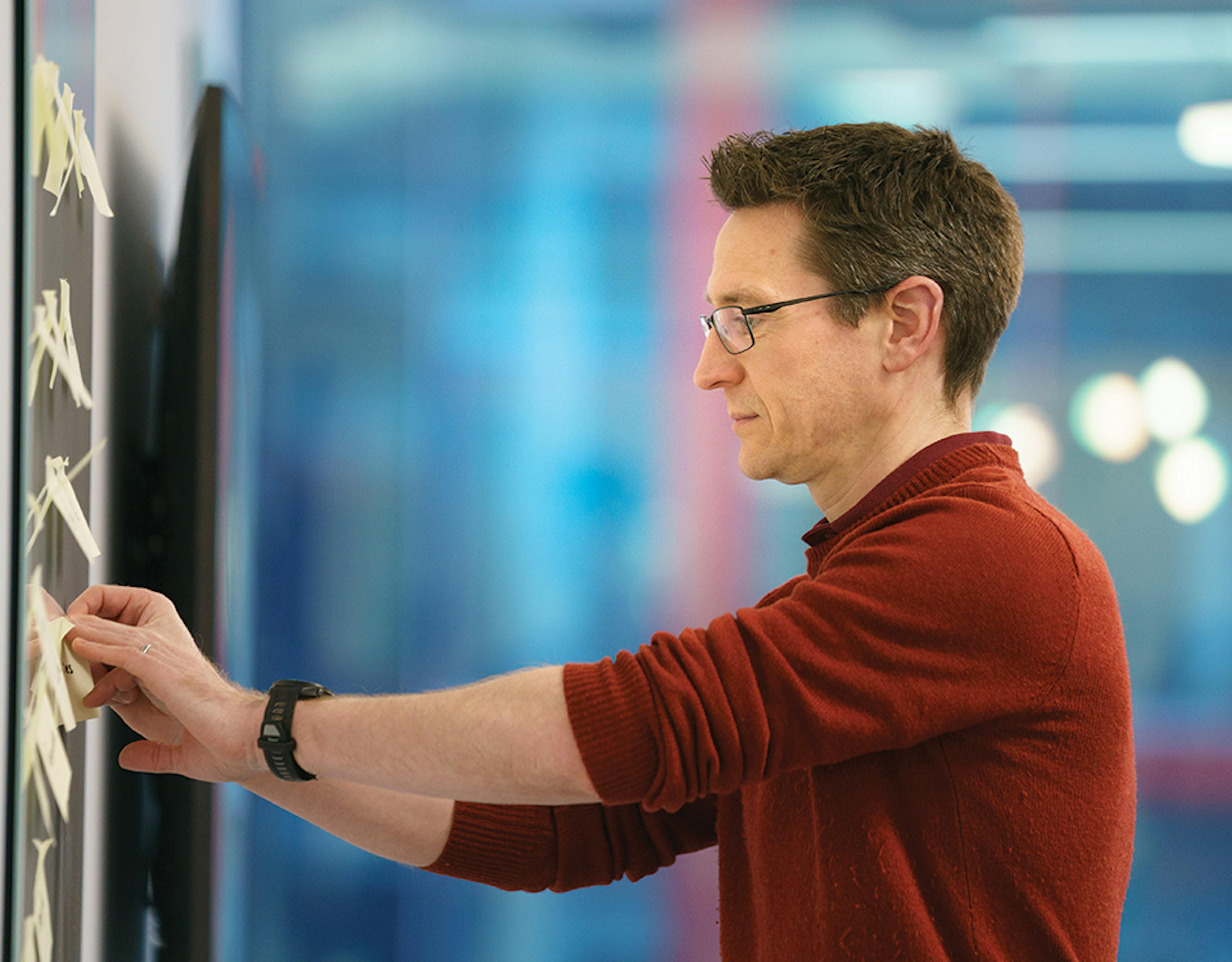 Man adding sticky notes to whiteboard
