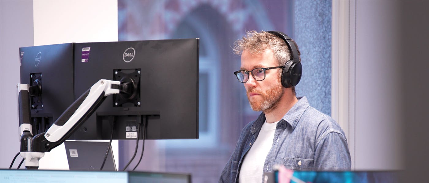 Person wearing headphones looking at computer monitor